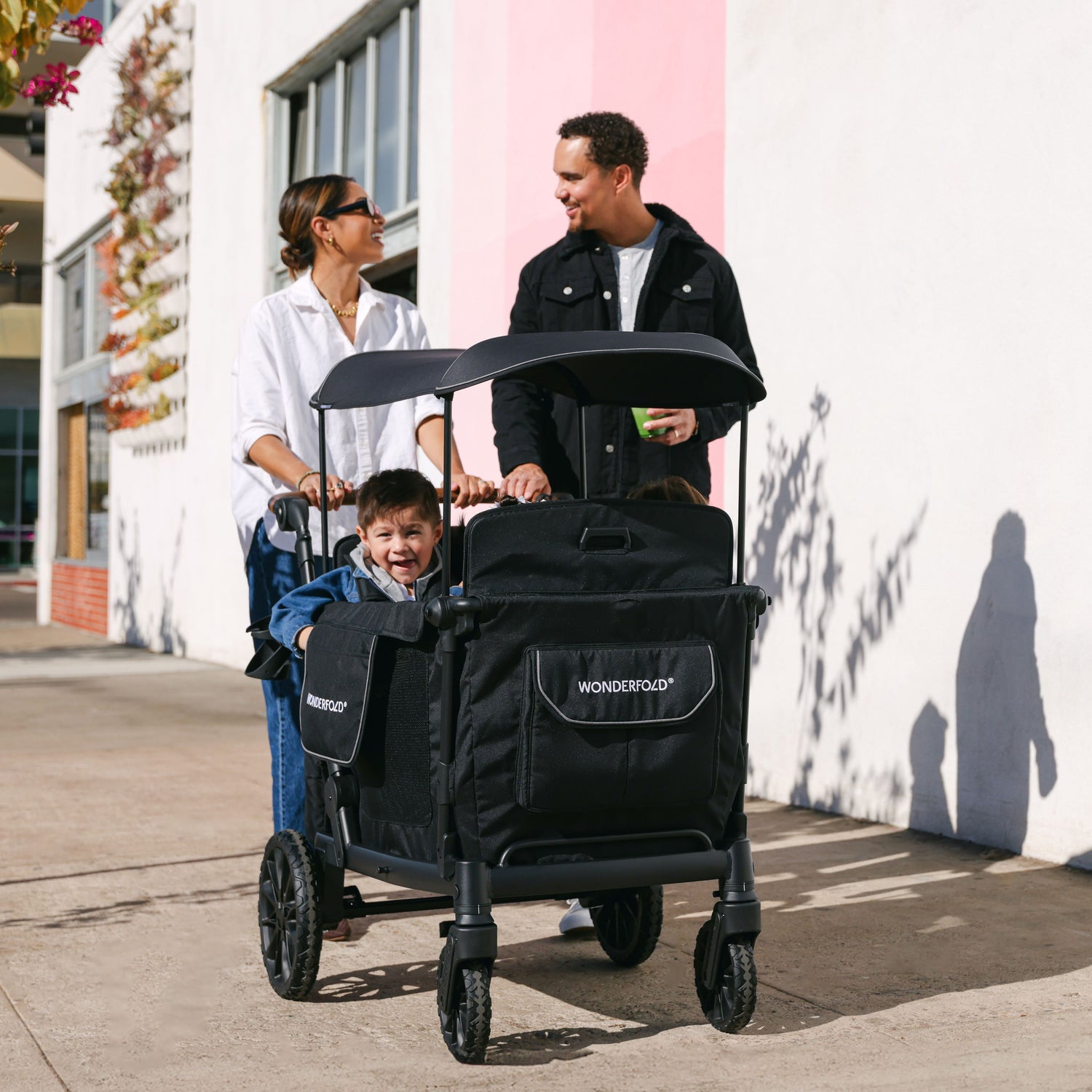 A family walking with the WonderFold L4 stroller wagon, highlighting its durable and stylish black design
